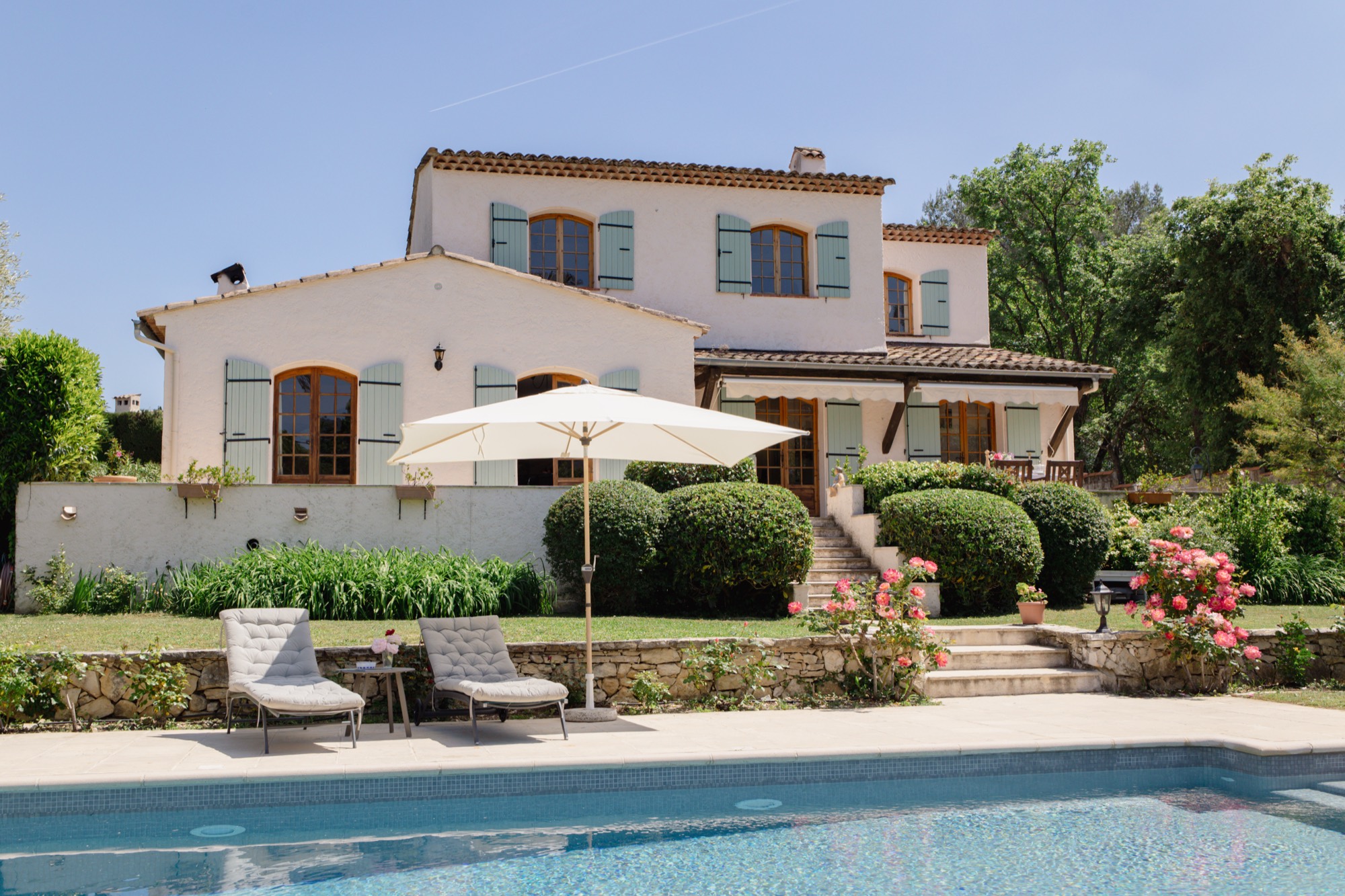 Außenansicht der Villa Le Bastidon mit Pool, Rasen und Blick auf die Berge